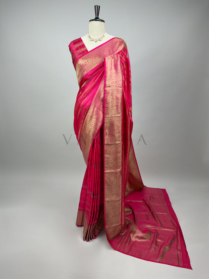 Pink saree with gold border on a mannequin against a gray background Full-length view of an exquisite Rani Pink Tanchoi Silk Saree with intricate gold thread weaving, elegantly draped on a mannequin for wedding and festive wear.

