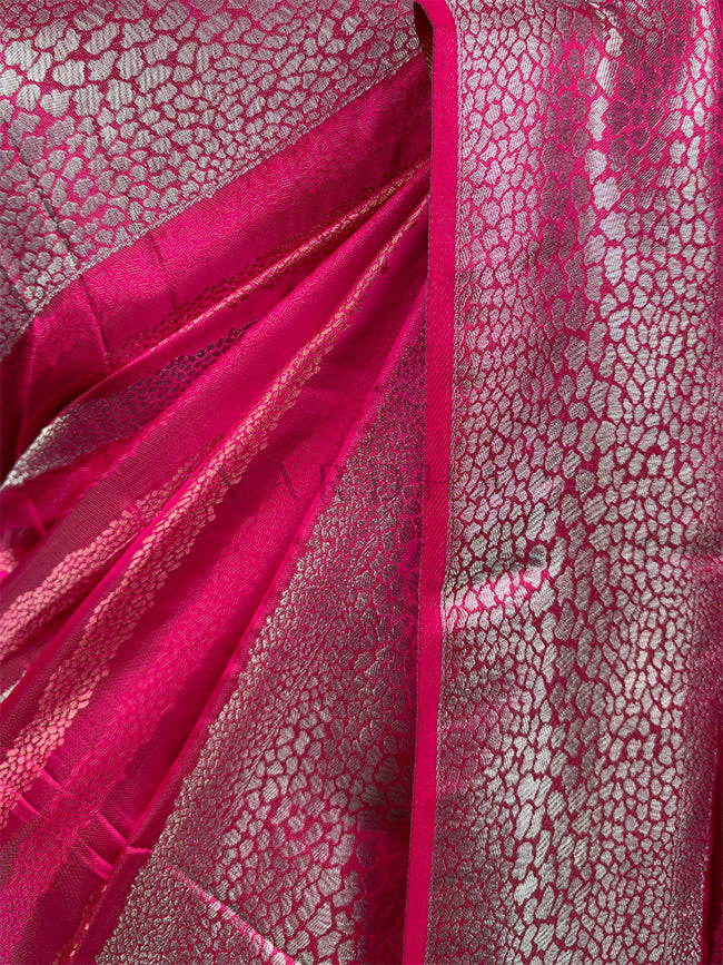 Close-up of pink fabric with a textured pattern Detailed close-up of the luxurious Rani Pink Tanchoi Silk fabric, showcasing the fine craftsmanship of the intricate metallic thread weaving and textured pattern.

