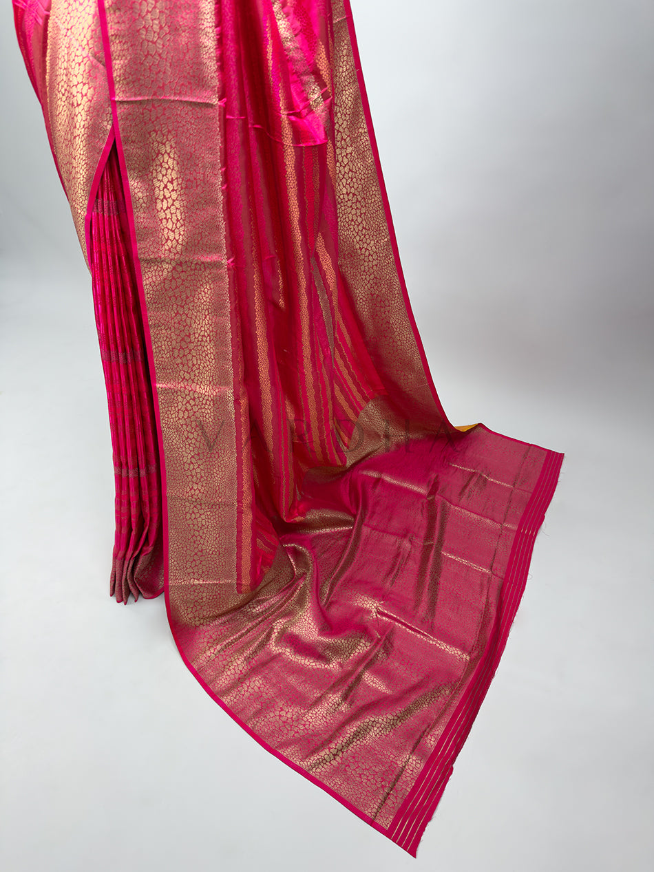 Pink saree with gold patterns on a white background A sprawling view of the richly decorated pallu of a Rani Pink Tanchoi Silk Saree, featuring dense thread work and a shimmering finish ideal for bridal wear.


