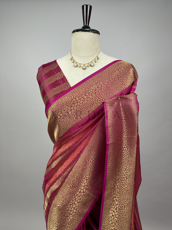 Saree with gold and wine pattern on a mannequin against a gray background A closer half-torso view of the draped Wine Tanchoi Silk Saree on a mannequin, highlighting the meticulously detailed weaving patterns across the chest and shoulder drape. The image accentuates the rich metallic luster of the gold threads over the deep burgundy wine silk, complemented by an elegant kundan statement necklace for a festive wedding ensemble.