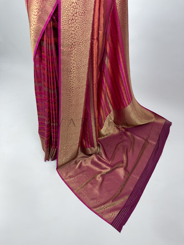 A targeted look at the lower section of the Wine Tanchoi Silk Saree, focusing on the neat front pleats and the grand pallu pooling on the floor. The design showcases alternating woven bands of wine and gold threads, with a deep magenta edge that defines the elegant flow and structured drape of this designer wedding attire.