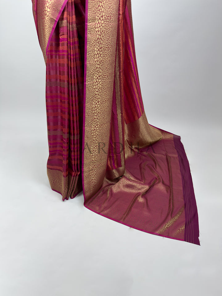 A focused view of the flowing pallu and lower border of the Wine Tanchoi Silk Saree spread out elegantly. The image showcases the heavy, shimmering gold thread weaving patterns across the wine silk base, illustrating the sophisticated design finish and rich heritage of traditional Banarasi style handloom sarees.