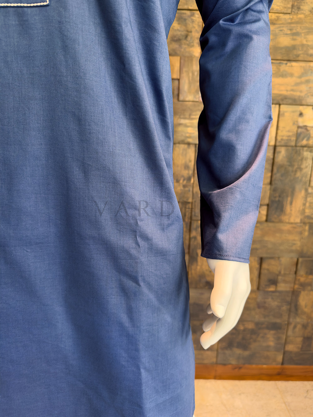 Blue garment on a mannequin against a wooden paneled wall. Premium breathable cotton kurta in a smooth French Blue finish, highlighting the crisp drape and high-quality tailoring.