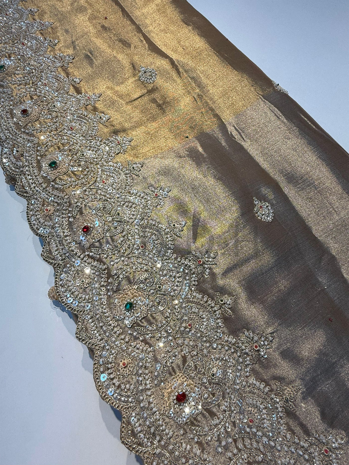 Artistic shot of Off White Saree with vibrant thread embroidery in red, pink, and green.
