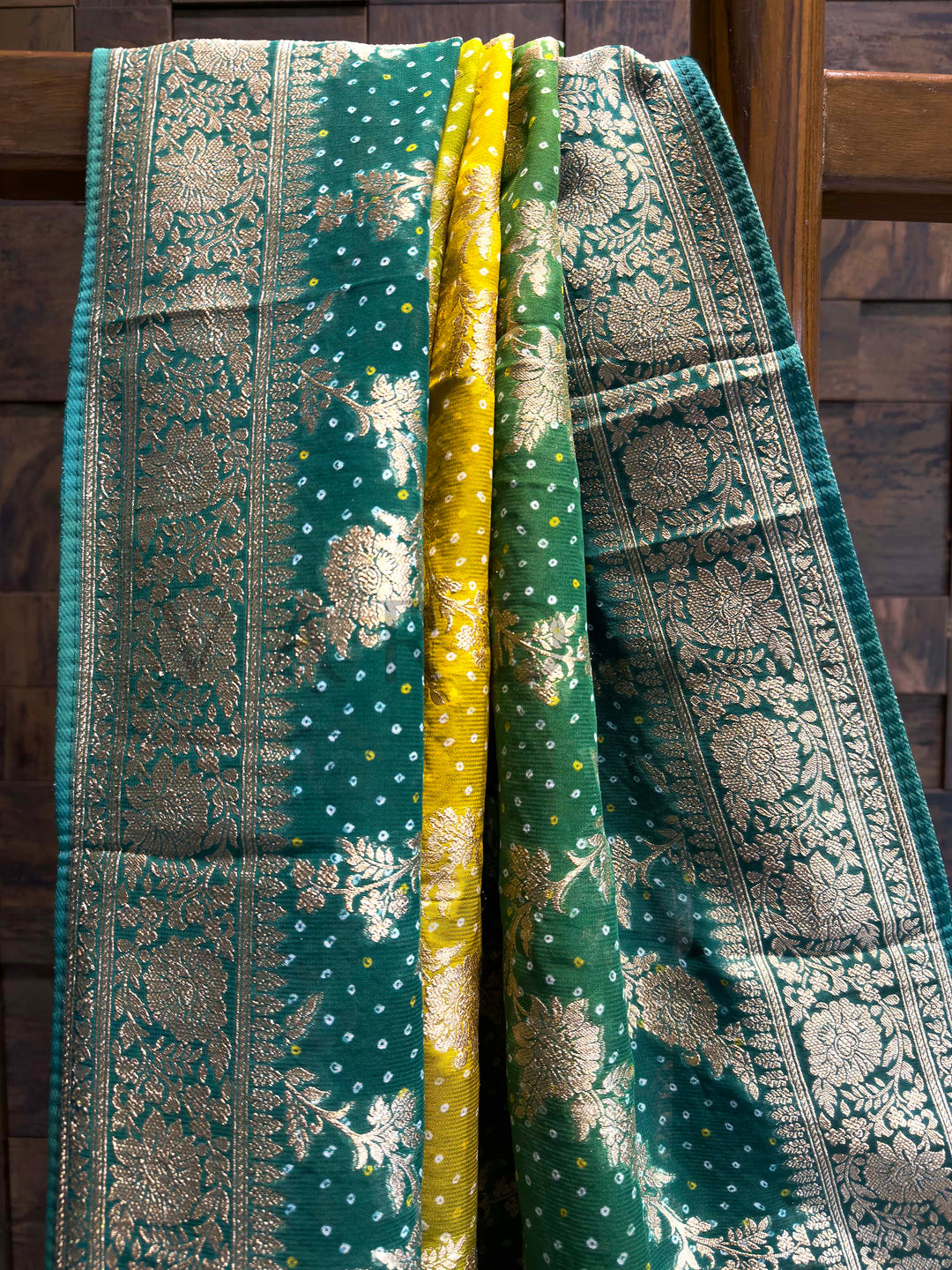Green and gold patterned fabric draped over a wooden surface