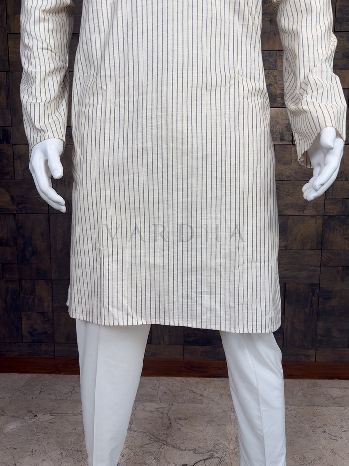 Mannequin wearing a white pinstripe coat and pants against a wooden paneled wall.