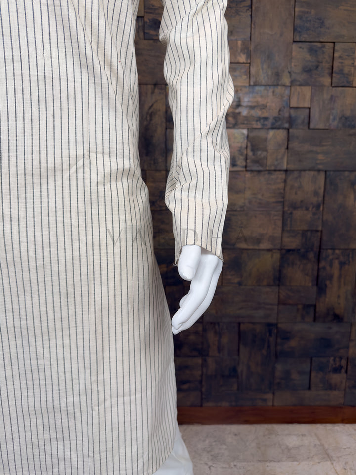 Mannequin wearing a white striped shirt against a textured brown wall.