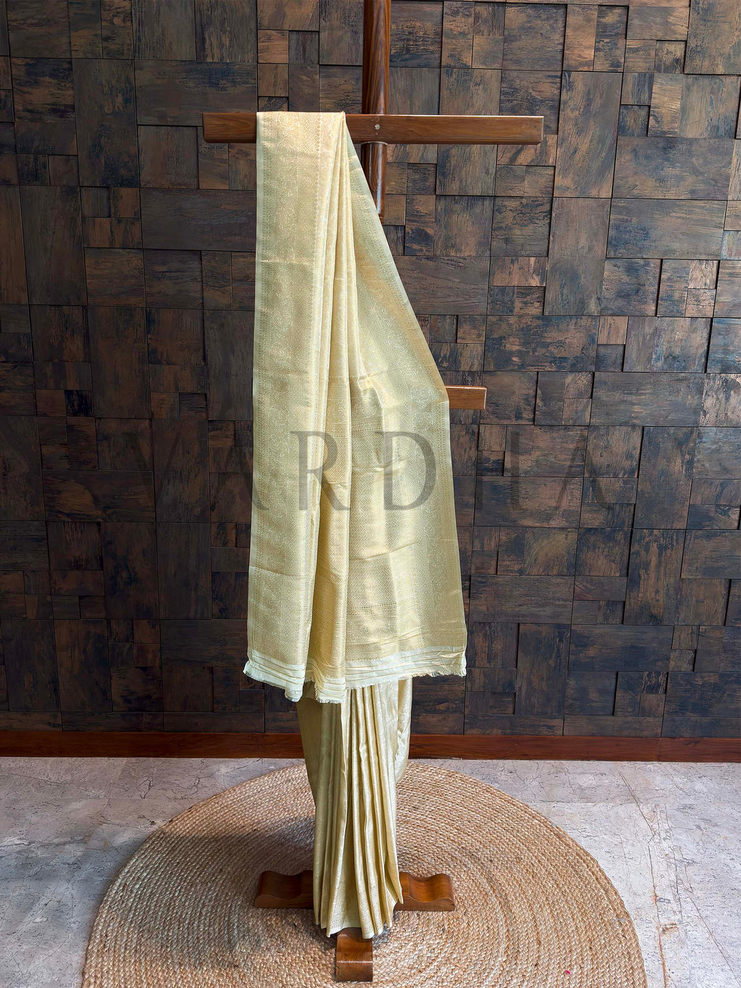 Ivory champagne Kanjivaram art silk saree on stand with golden zari floral jaal and geometric brocade borders, rich pallu and crisp pleats.