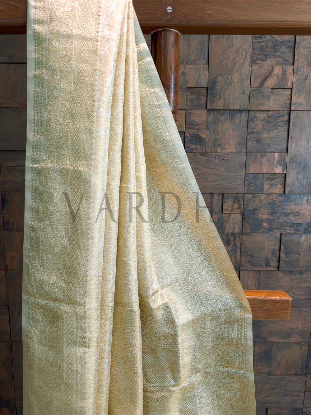 Close-up of ivory-gold saree body showing dense tone-on-tone zari floral jaal with slim selvedge, luminous art silk texture.
