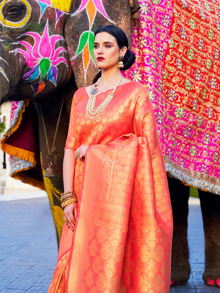 Heavy woven zari detailing on kanjivaram silk in coral orange base with temple border. South Indian bridal saree in coral and gold with jacquard body and sheen pallu.