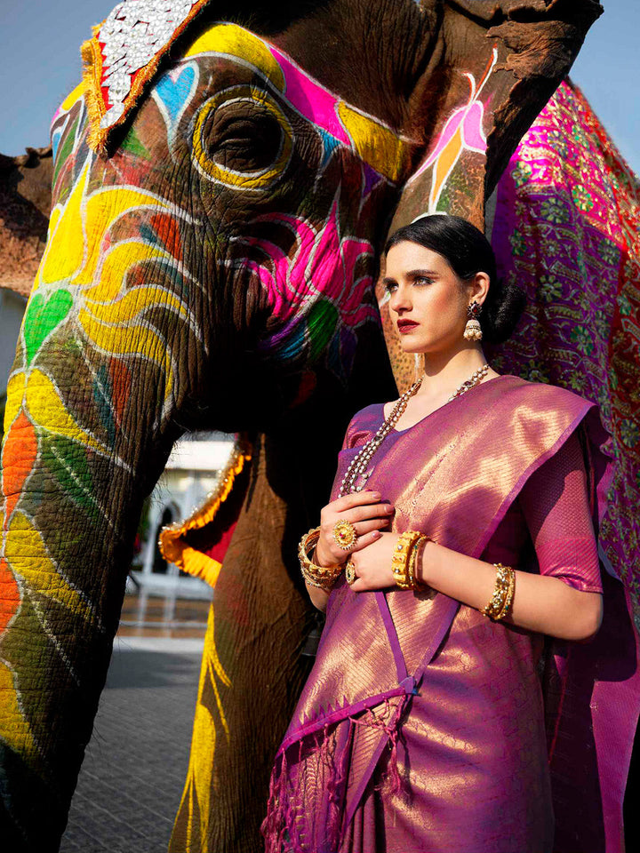 Traditional wedding saree in Rani Pink–Purple featuring rich zari work and heritage charm. Rani Pink–Purple silk saree with zari woven paisley and floral motifs, bridal ceremony ready.