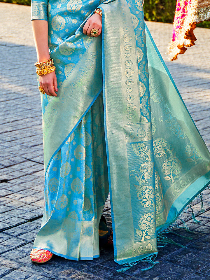 Traditional wedding saree in Teal Blue–Green featuring rich zari work and heritage charm. Teal Blue–Green silk saree with zari woven paisley and floral motifs, bridal ceremony ready.