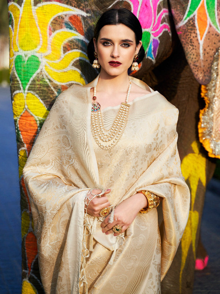 Traditional wedding saree in Ivory–Champagne Gold featuring rich zari work and heritage charm. Ivory–Champagne Gold silk saree with zari woven paisley and floral motifs, bridal ceremony ready.