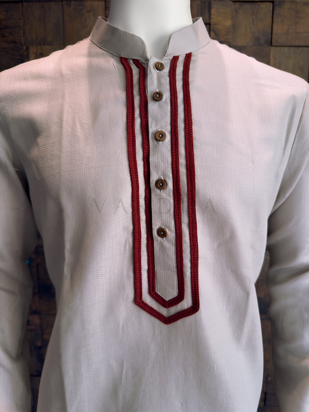 Grey kurta with maroon embroidery on a wooden background Detailed view of the dense maroon corded embroidery and rustic designer buttons on the grey cotton kurta.
