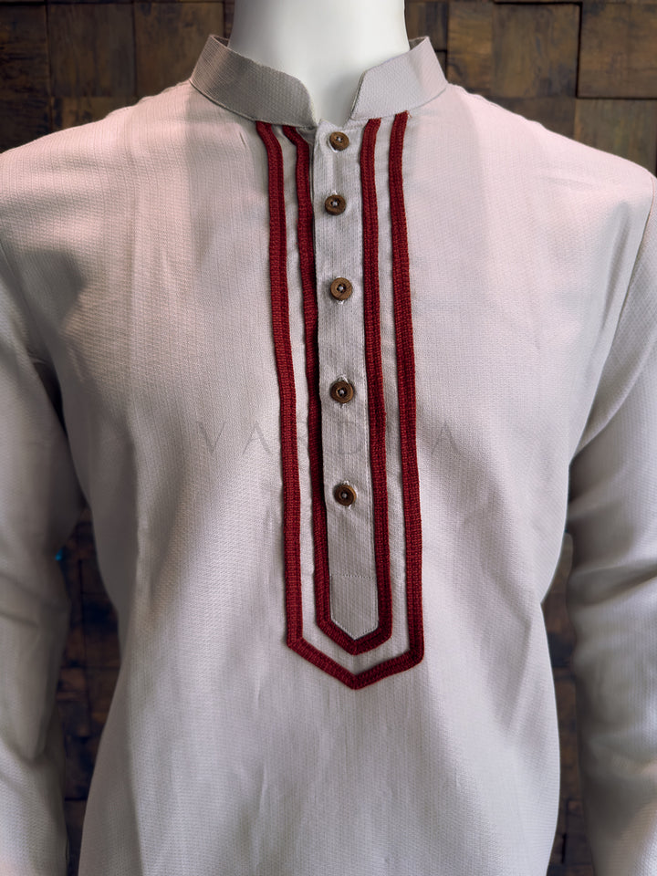 Grey kurta with maroon embroidery on a wooden background Detailed view of the dense maroon corded embroidery and rustic designer buttons on the grey cotton kurta.