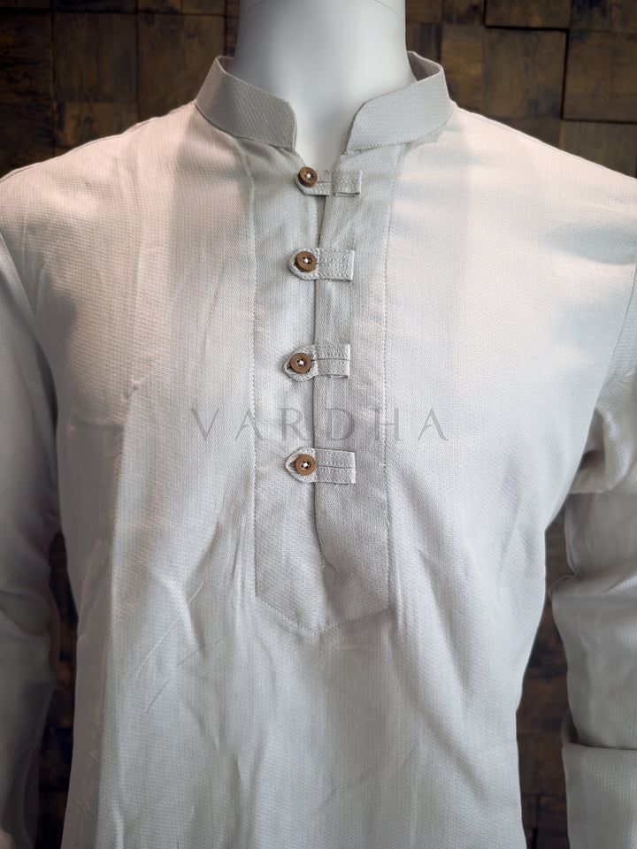 Grey kurta with brown buttons on a mannequin against a wooden background, featuring the brand &