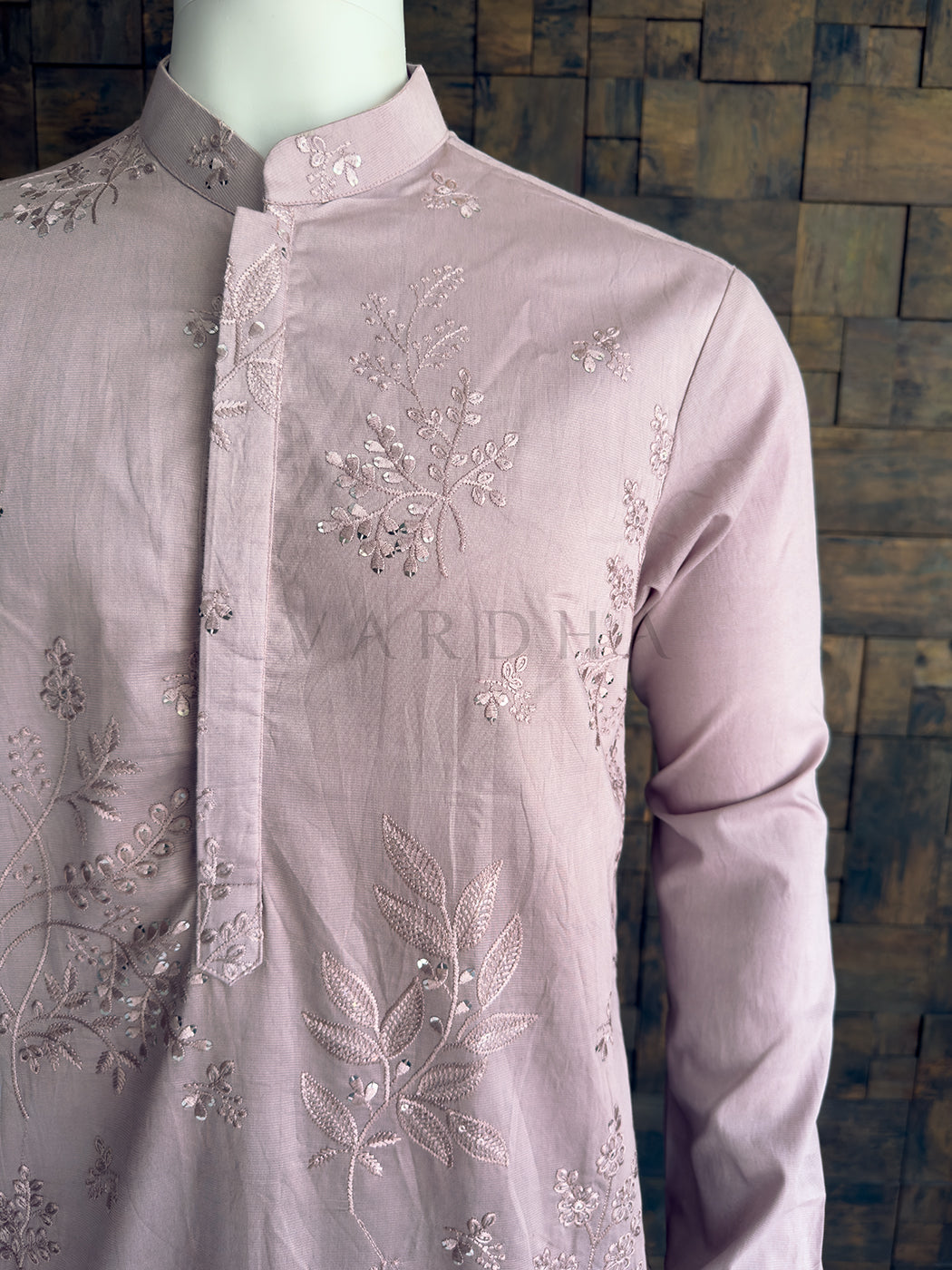 Light purple embroidered shirt on a mannequin against a wooden paneled wall. Front torso view emphasizing the shimmering sequin floral motifs and the seamless concealed placket on the luxurious pastel purple viscose fabric.