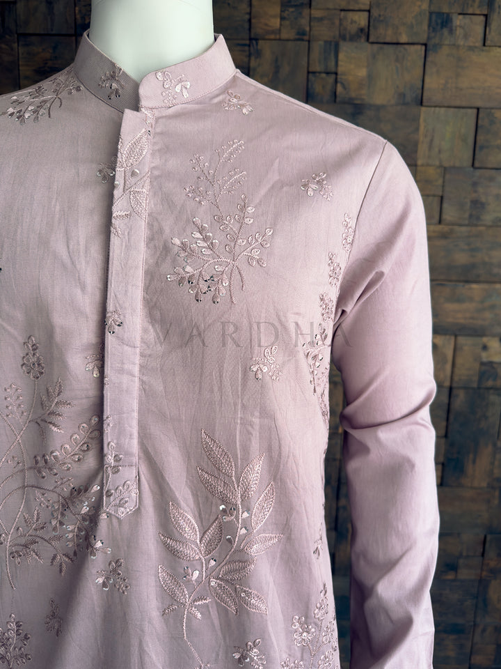 Light purple embroidered shirt on a mannequin against a wooden paneled wall. Front torso view emphasizing the shimmering sequin floral motifs and the seamless concealed placket on the luxurious pastel purple viscose fabric.