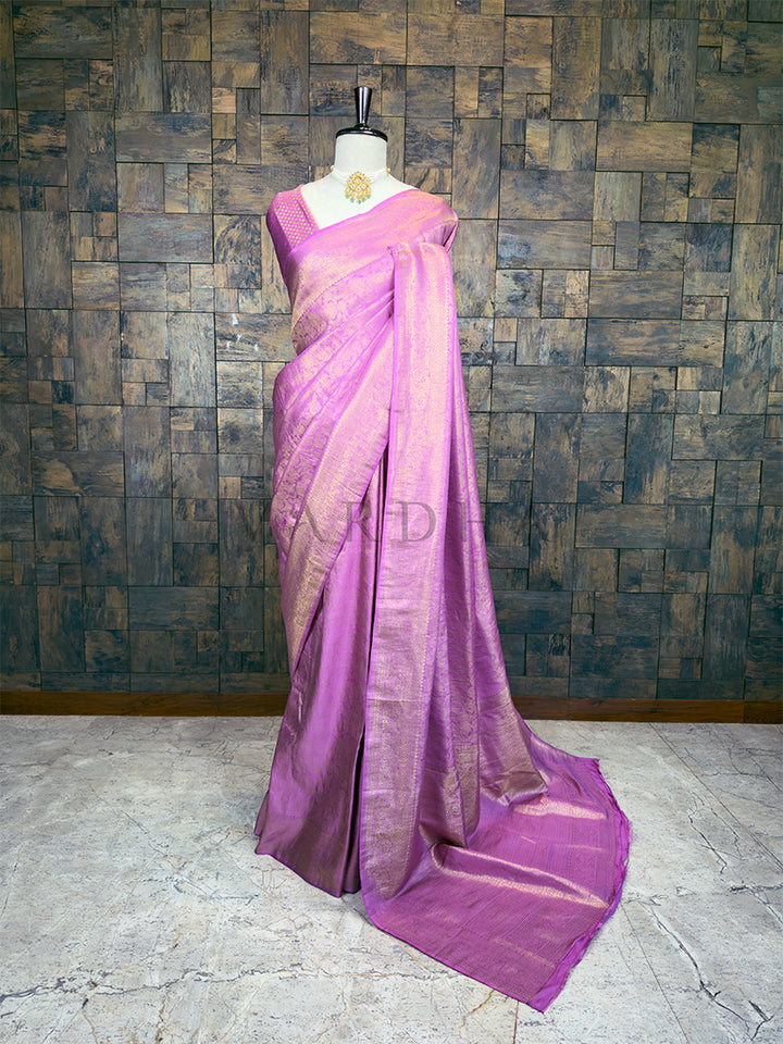 Purple saree on a mannequin against a textured wall. House of Vardha Lilac Kanjivaram Silk Saree featuring an intricate Gold Zari Weave with floral motifs, elegantly draped on a mannequin. We offer Ready to wear, Pre drape service, Saree Add on, Custom Stitched Blouse, Fall and Edging, Gift Packaging at Complimentary Price!