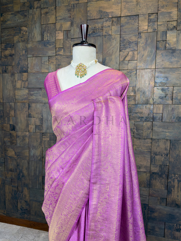 Purple saree with gold border on a mannequin against a wooden paneled wall. Lustrous Lilac Kanjivaram Silk Saree by House of Vardha showcasing heavy traditional Gold Zari Weave craftsmanship and a rich border. We offer Ready to wear, Pre drape service, Saree Add on, Custom Stitched Blouse, Fall and Edging, Gift Packaging at Complimentary Price!