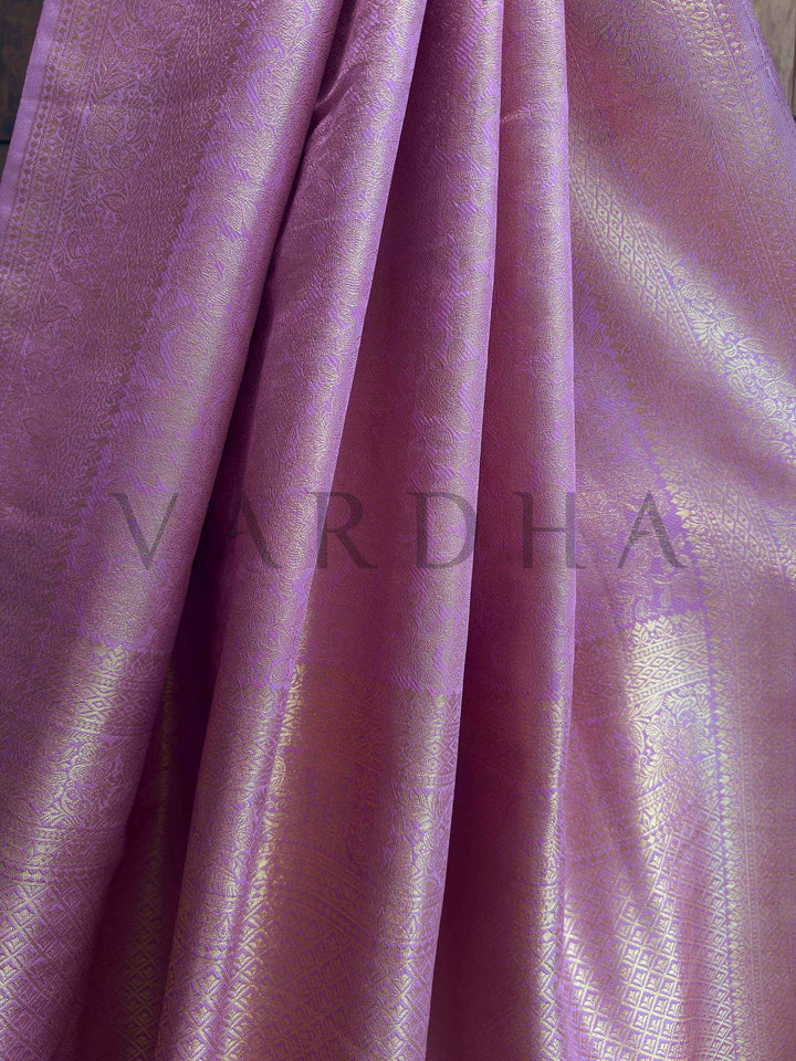 Angle detail capturing high-shine pallu with floral vines and geometric zari motifs over pastel lavender base, elegant fall. Authentic Indian ethnic wear featuring a striking Lilac Kanjivaram Silk Saree richly woven with golden threads to create a luxurious look by House of Vardha. We offer Ready to wear, Pre drape service, Saree Add on, Custom Stitched Blouse, Fall and Edging, Gift Packaging at Complimentary Price!