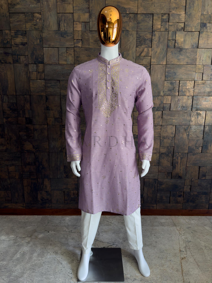 Mannequin wearing a mauve kurta with gold embroidery against a wooden paneled wall. Stylish lilac cotton kurta for men featuring gold mukaish embroidery perfect for festive celebrations