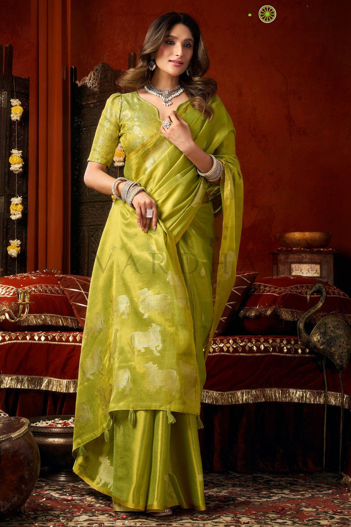 Woman in a green saree posing in an ornate room. Stylish front drape of the lime green heavy tissue saree showing its beautiful texture, perfect for haldi ceremonies and wedding wear.