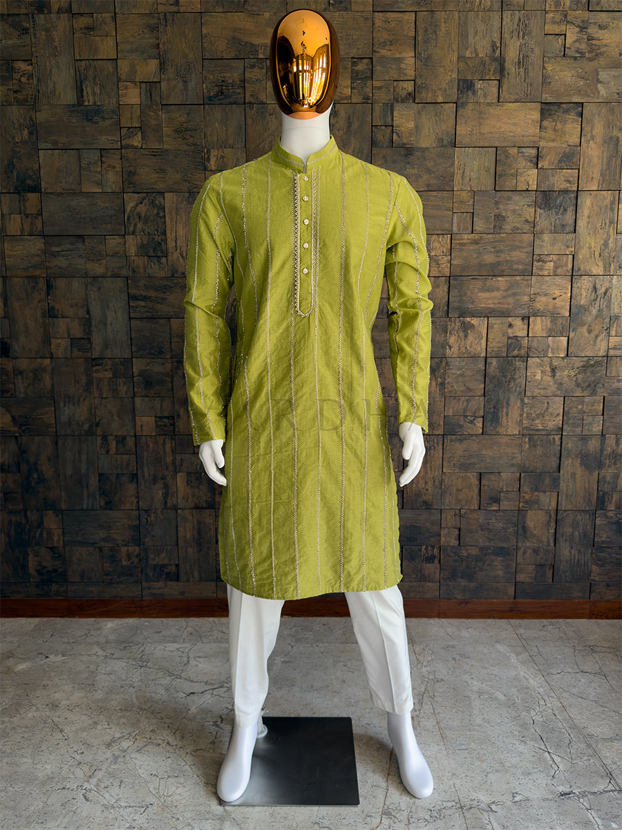 Mannequin wearing a green kurta against a wooden paneled wall. Front view of a man wearing a House of Vardha lime green viscose kurta featuring vertical metallic chevron embroidery. Perfect men's ethnic wear for Haldi, Mehendi, and daytime festive celebrations.