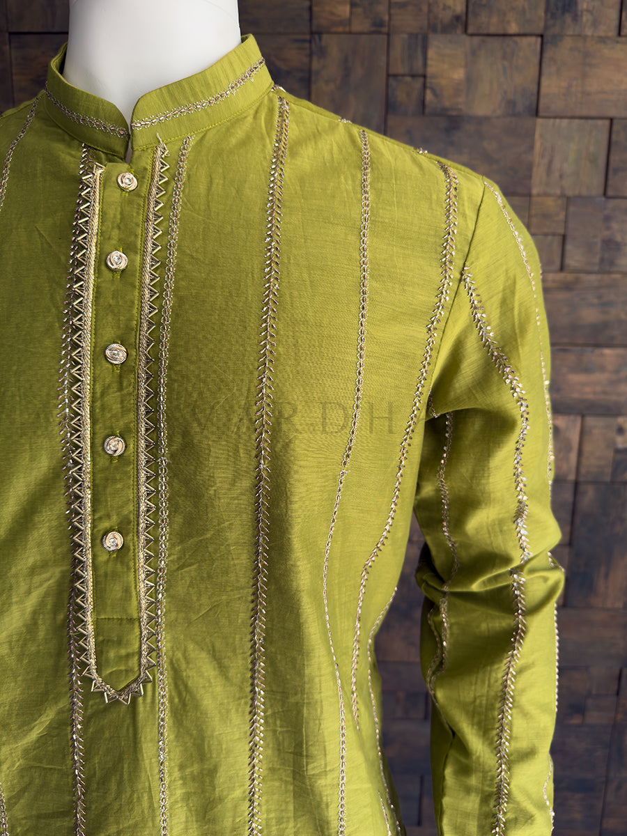 Green kurta with intricate embroidery on a wooden block background. Side angle of the tailored green viscose kurta for men, emphasizing the structured fit, metallic threadwork, and elegant mandarin collar perfect for traditional events.