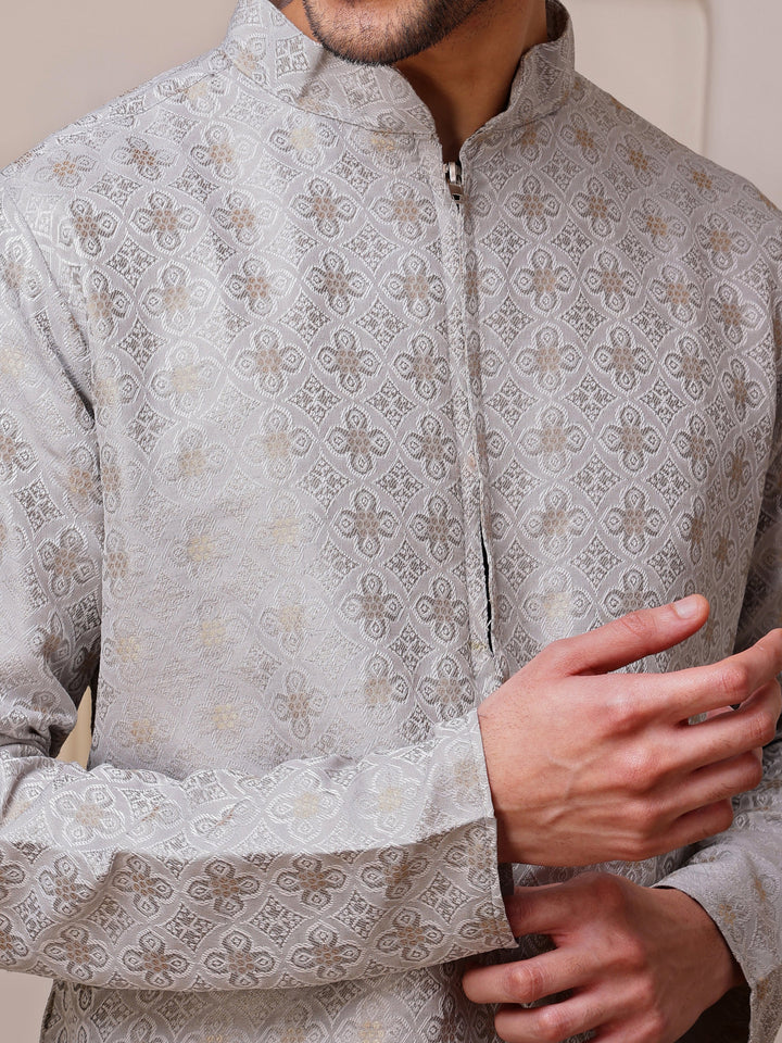 Full view of a man wearing a sophisticated light grey kurta with gold weave and a concealed zipper placket