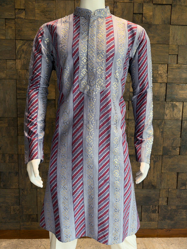 Traditional patterned kurta on a mannequin against a wooden paneled wall.