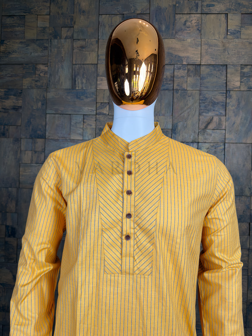 Mannequin wearing a yellow striped shirt against a textured dark wall