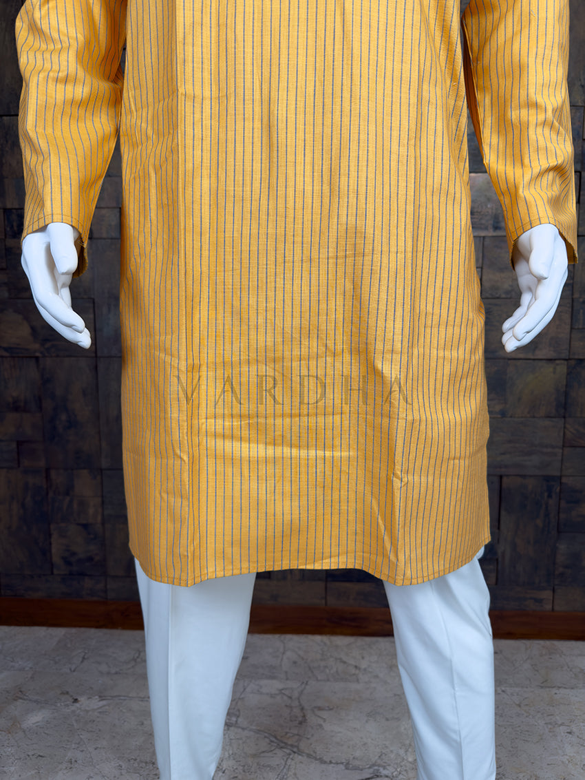 Yellow striped kurta with white pants on a mannequin against a brick wall.