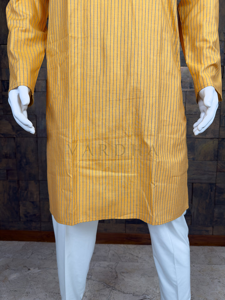 Yellow striped kurta with white pants on a mannequin against a brick wall.