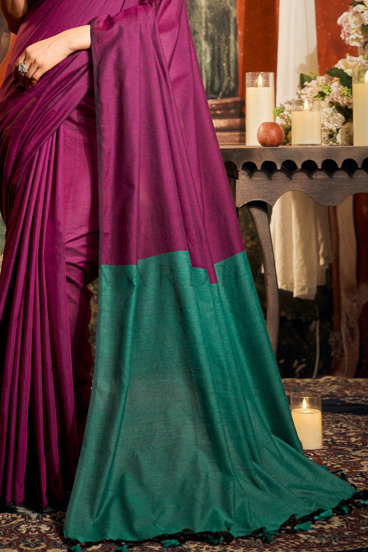 Purple and green saree draped over a person with a decorative background. Close-up of the perfectly pleated texture of the dark pink mal cotton saree meeting the solid emerald green contrast pallu.