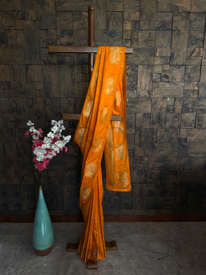 Mustard orange satin saree for women with golden zari elephant motifs and glossy drape.