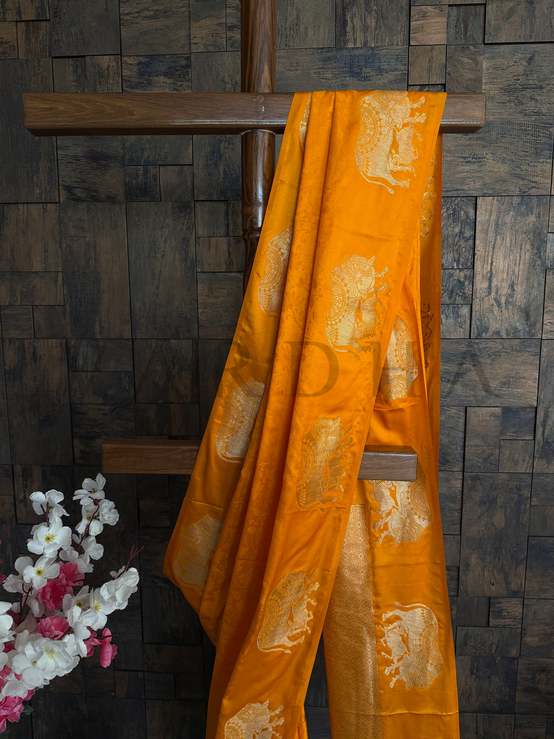 Rich orange satin silk saree with sheen texture and regal zari animal motifs.

