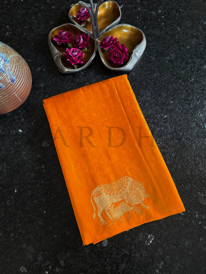 Women’s partywear satin saree in mustard orange with golden woven detailing.

Vibrant orange satin saree with lustrous drape and handcrafted elephant zari work.