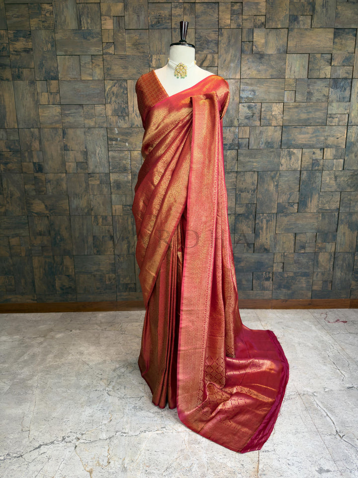 Maroon saree with gold border on a mannequin against a textured wall. House of Vardha premium maroon silk saree featuring heavy gold zari brocade work and a wide ornate border draped on a mannequin.