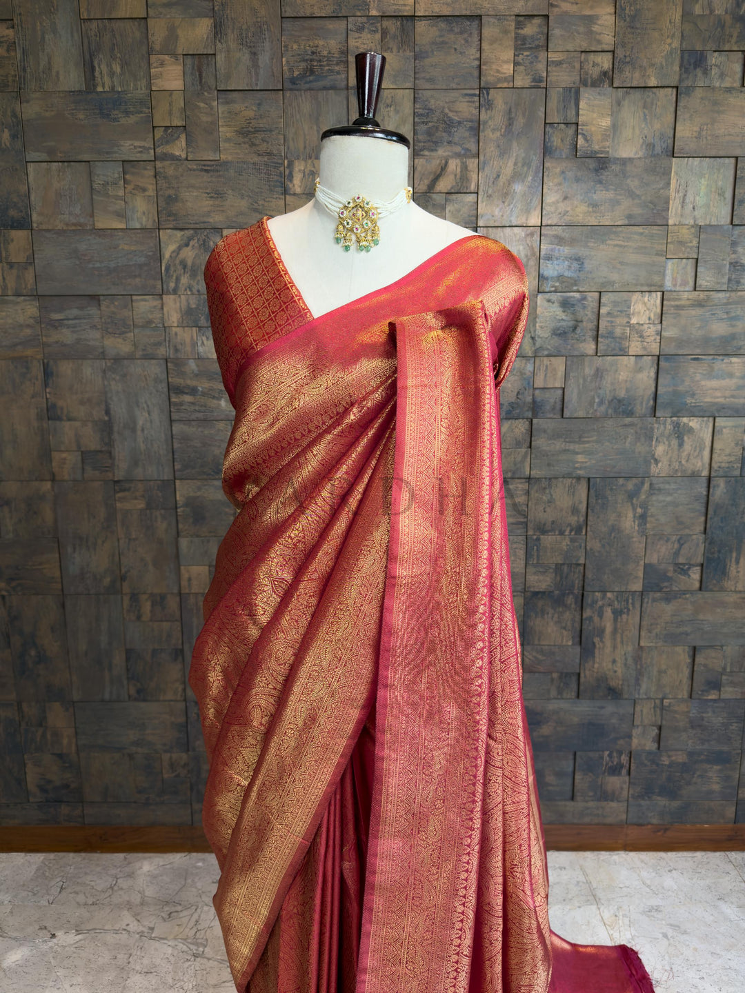 Elegant Maroon and gold bridal saree by House of Vardha showcasing intricate traditional zari motifs for wedding wear. Maroon saree with gold border on a mannequin against a textured wall.