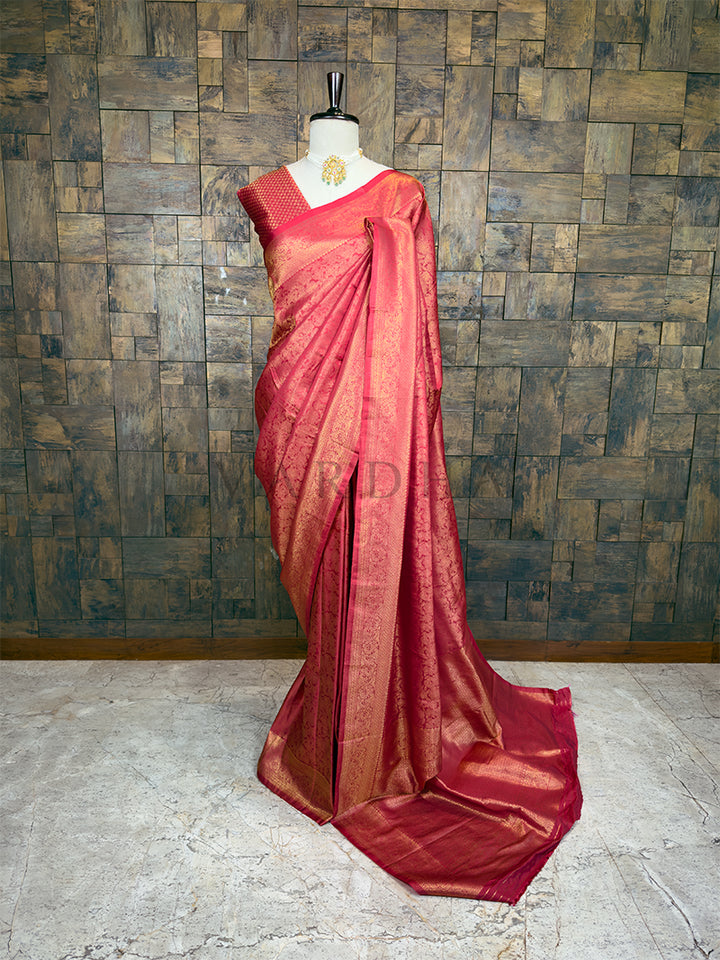 Maroon saree with gold border on a mannequin against a textured wall. House of Vardha premium deep copper-red silk saree showcasing all-over gold zari brocade work draped on a mannequin. We offer Ready to wear, Pre drape service, Saree Add on, Custom Stitched Blouse, Fall and Edging, Gift Packaging at Complimentary Price!