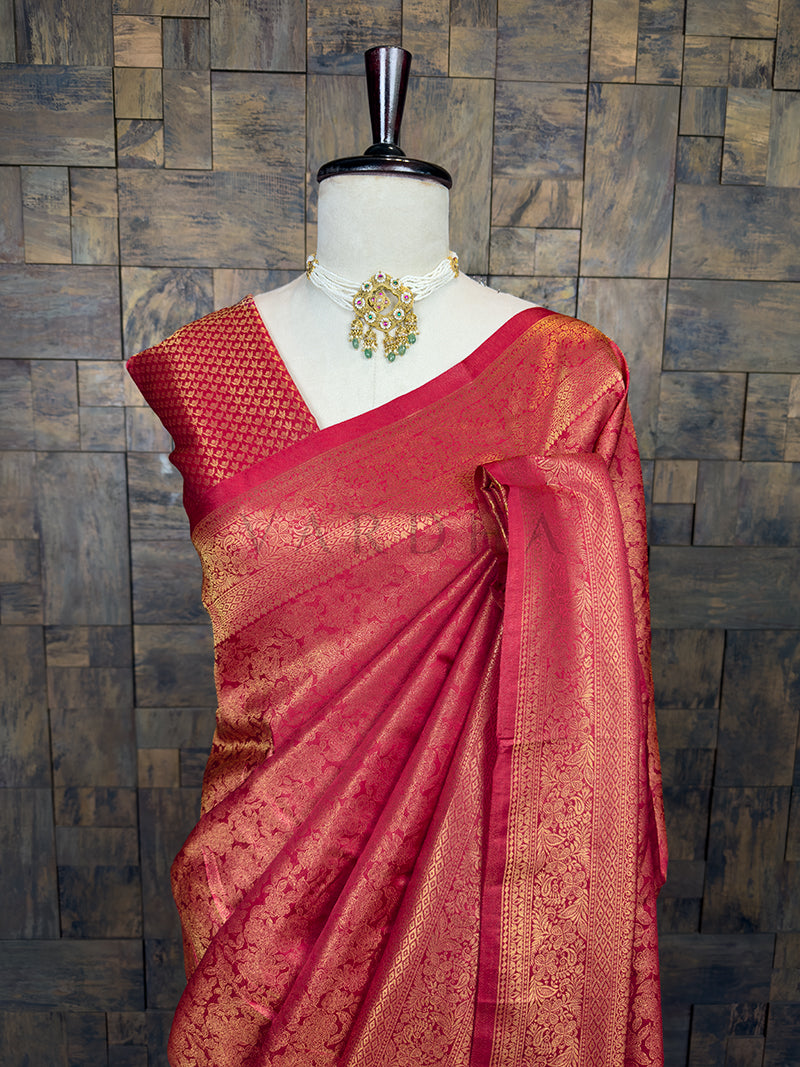Maroon saree with gold patterns on a mannequin against a wooden paneled wall. Elegant maroon-toned festive saree by House of Vardha featuring intricate traditional gold woven floral motifs. We offer Ready to wear, Pre drape service, Saree Add on, Custom Stitched Blouse, Fall and Edging, Gift Packaging at Complimentary Price!