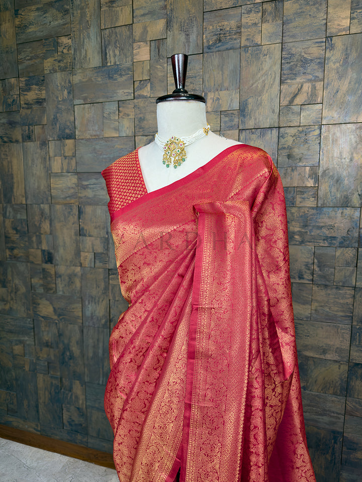 Maroon saree with gold patterns on a mannequin against a textured wall. Close-up of House of Vardha rich copper-red silk saree highlighting detailed gold zari craftsmanship on the pleats and body. We offer Ready to wear, Pre drape service, Saree Add on, Custom Stitched Blouse, Fall and Edging, Gift Packaging at Complimentary Price!
