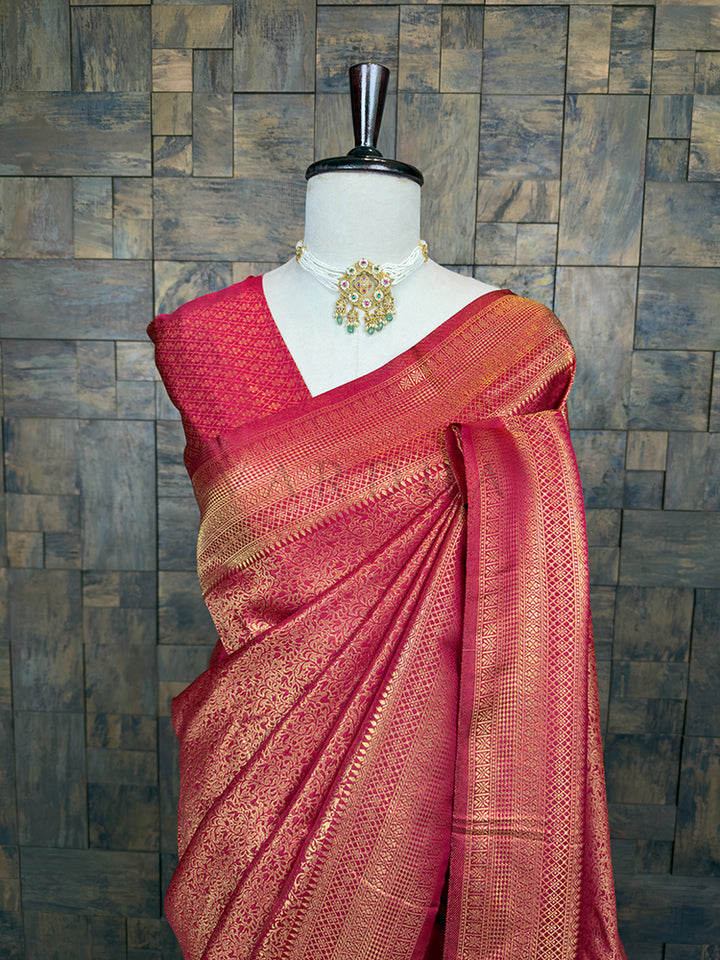 Maroon saree with gold patterns on a mannequin against a textured wall. Lustrous Maroon Golden Zari Kanjivaram Silk Saree by House of Vardha showcasing dense gold zari craftsmanship and a rich, matching border. We offer Ready to wear, Pre drape service, Saree Add on, Custom Stitched Blouse, Fall and Edging, Gift Packaging at Complimentary Price!