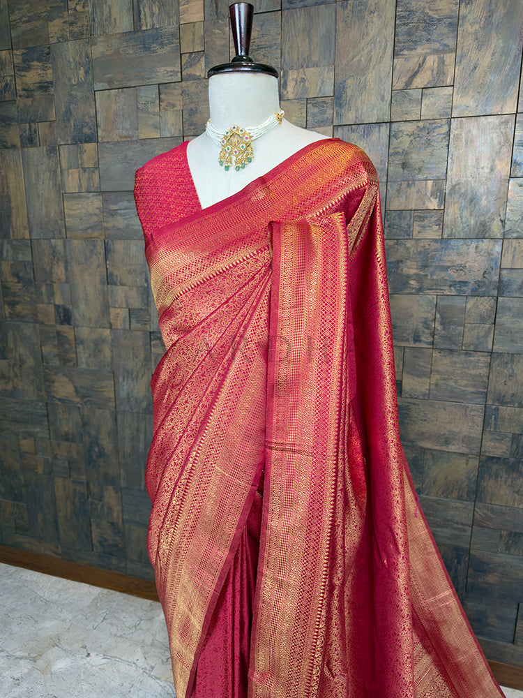 Maroon saree with gold patterns on a mannequin against a textured wall. Close-up view of the House of Vardha Maroon Golden Zari Kanjivaram Silk Saree highlighting the exquisite golden zari patterns on the pleats and body. We offer Ready to wear, Pre drape service, Saree Add on, Custom Stitched Blouse, Fall and Edging, Gift Packaging at Complimentary Price!