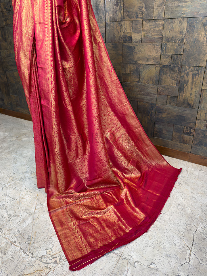 Maroon saree with gold border on a stone floor and tiled wall background. Elegant Maroon festive Kanjivaram Silk Saree from House of Vardha with a radiant golden zari weave, perfect for Indian weddings and bridal wear. We offer Ready to wear, Pre drape service, Saree Add on, Custom Stitched Blouse, Fall and Edging, Gift Packaging at Complimentary Price!