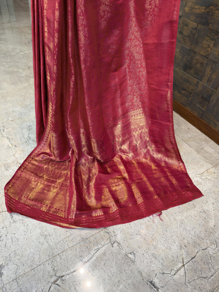 Red saree with gold patterns on a marble floor Luxurious Indian bridal saree in a deep pink-red tone from House of Vardha with heavy gold zari embellishments. We offer Ready to wear, Pre drape service, Saree Add on, Custom Stitched Blouse, Fall and Edging, Gift Packaging at Complimentary Price!