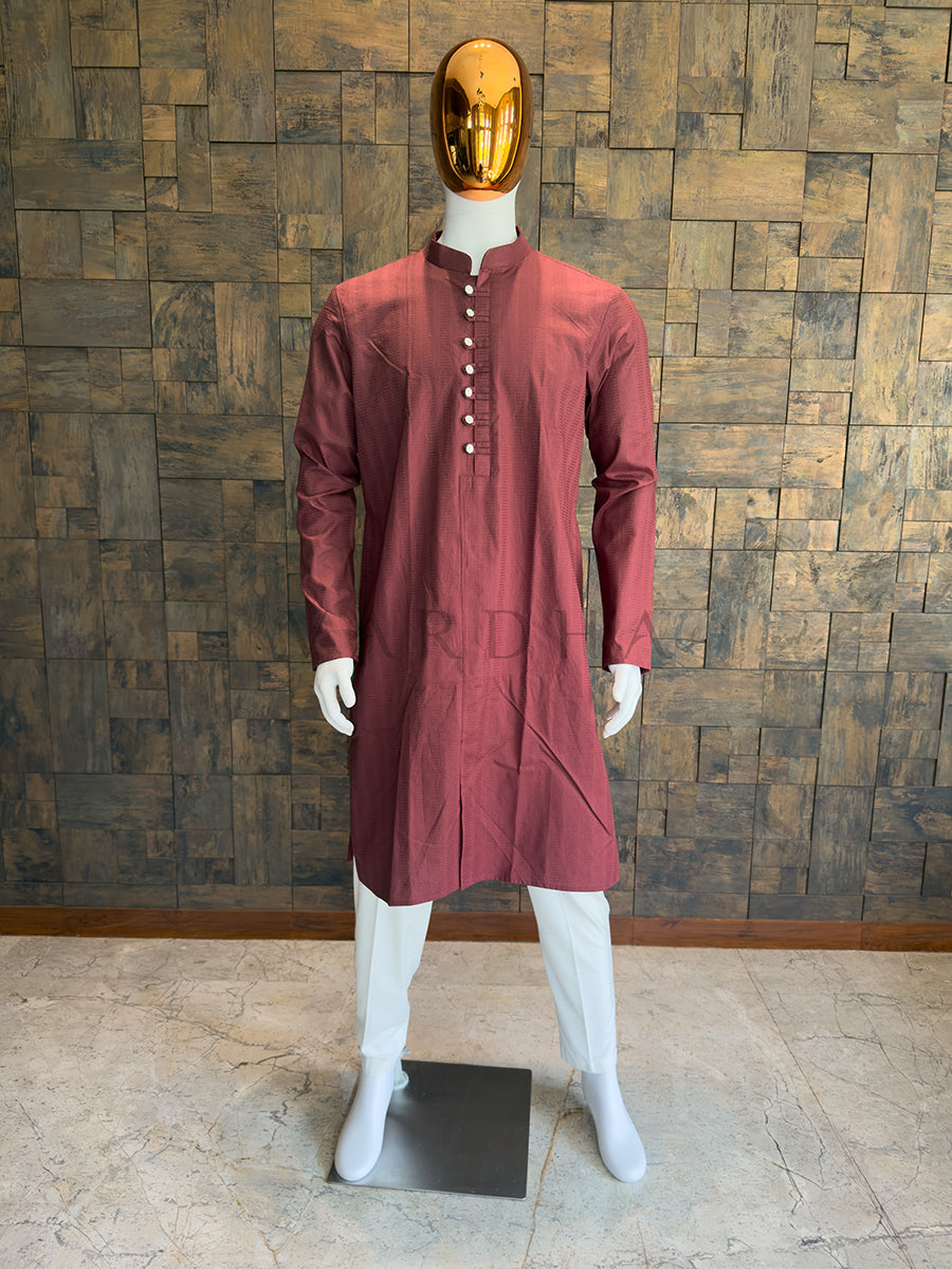 Maroon kurta on a mannequin against a wooden paneled wall. Regal Maroon knee-length kurta with sharp architectural tailoring, a Mandarin collar, and full sleeves ideal for evening weddings and formal receptions.