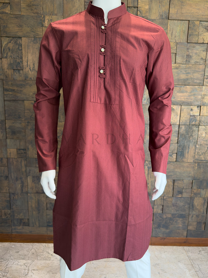Maroon kurta on a mannequin against a wooden paneled wall features a highly sophisticated, all-over woven vertical micro-stripe (dobby) texture. This tactile pattern gives the dark maroon fabric a premium, slightly heavyweight appearance and subtly elongates the wearer&