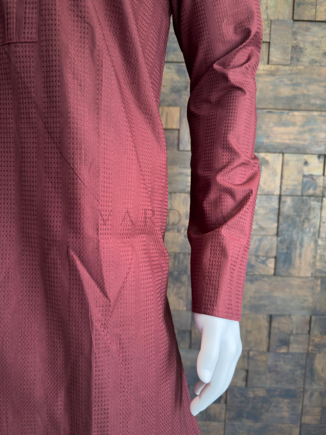 Maroon textured shirt on a mannequin against a wooden paneled wall. A classic knee-length Long Kurta with full, straight sleeves and a clean hemline.